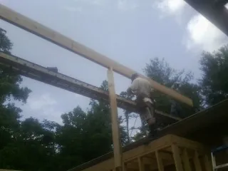 Carpenter setting a ridge beam over a new addition frame — Ice Dam Removal by Roofing Brothers in Corinth