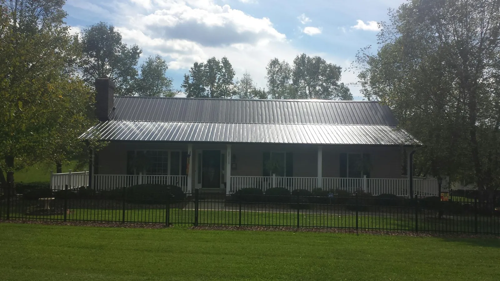 Gray metal roof on a brick ranch with a full width front porch — Gutter Guard Installation work by our crew in Corinth