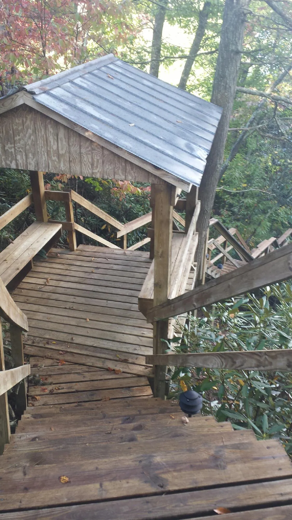 Metal roofed shelter over wooden steps on a wooded walkway — Skylight Repair & Installation work by our crew in Corinth